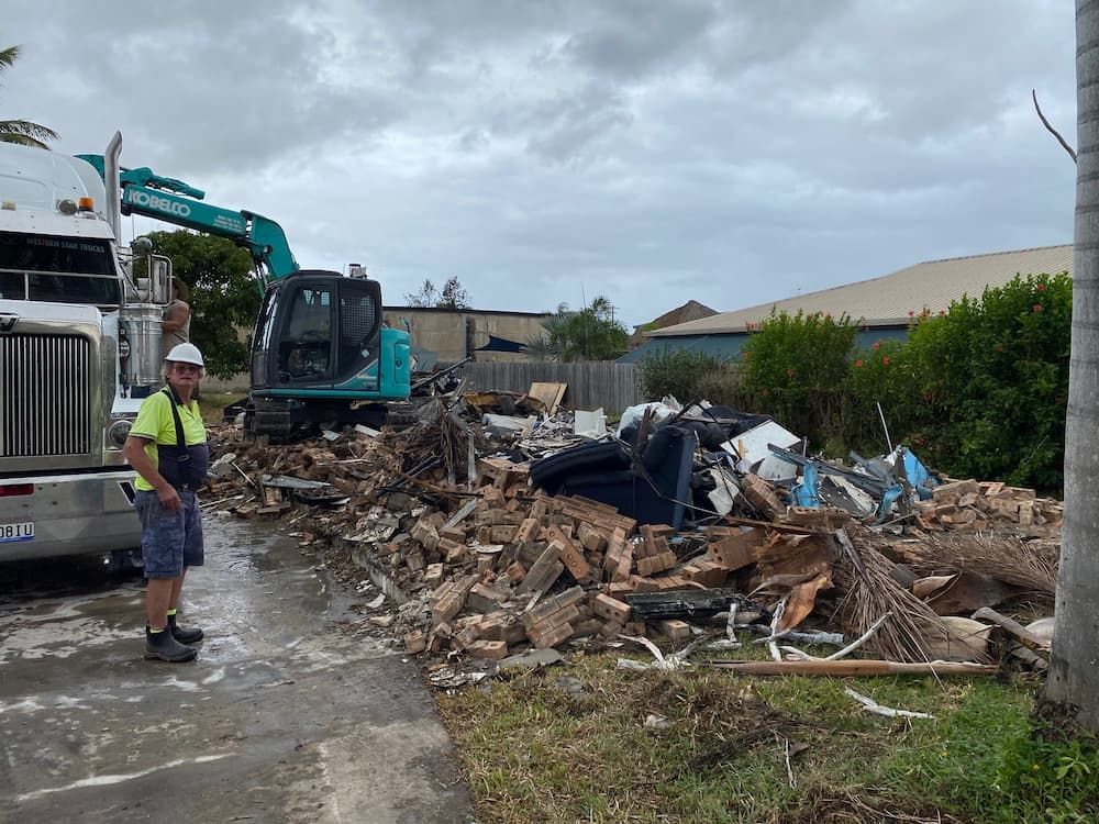 An Excavator Clearing a Pile of Brick Rubble From a Building Demolition — Integrabuild in Airlie Beach, QLD
