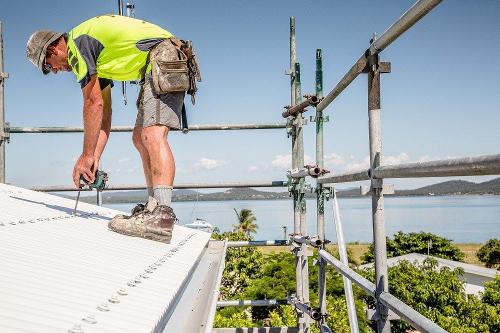 A Man Is Working On A Roof On Top Of A Scaffolding — Integrabuild in Bowen, QLD