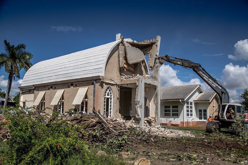 A House Is Being Demolished By An Excavator — Integrabuild in Bowen, QLD