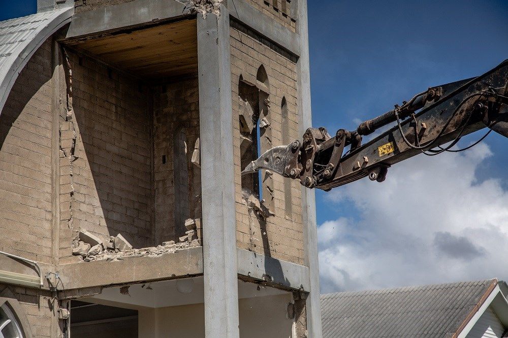 A Large Brick Building Is Being Demolished By A Crane — Integrabuild in Bowen, QLD