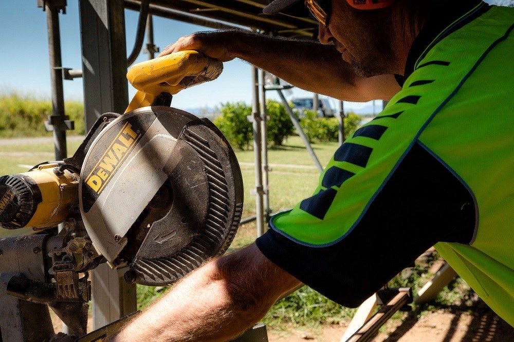 A Man Is Using A Dewalt Circular Saw To Cut A Piece Of Wood — Integrabuild in Bowen, QLD