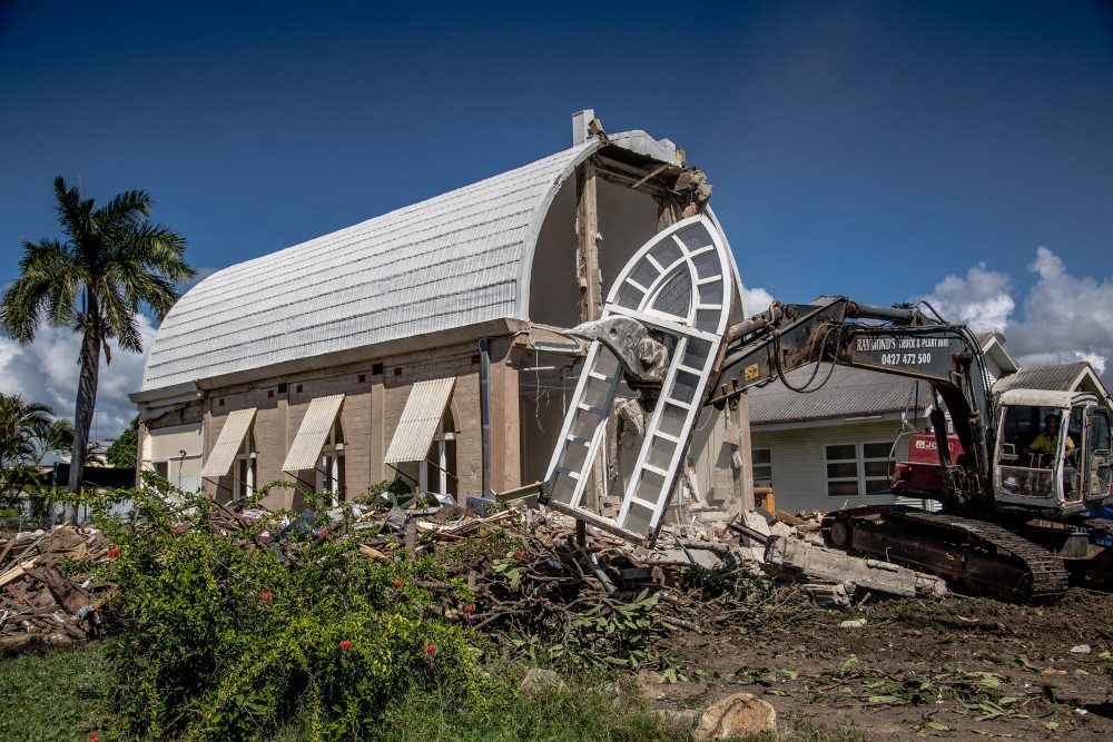 A Large Building Is Being Demolished By A Bulldozer — Integrabuild in Airlie Beach, QLD