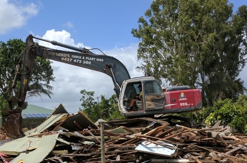 A Large Excavator Is Demolishing A Building — Integrabuild in Bowen, QLD