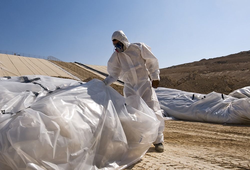 A Man In A Protective Suit Is Holding A Plastic Bag — Integrabuild in Airlie Beach, QLD