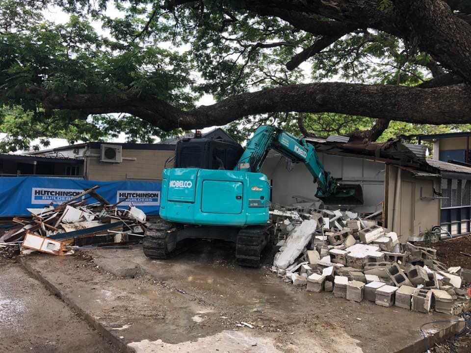 A Teal Excavator Demolishes a Building, Under a Large Tree — Integrabuild in Bowen, QLD