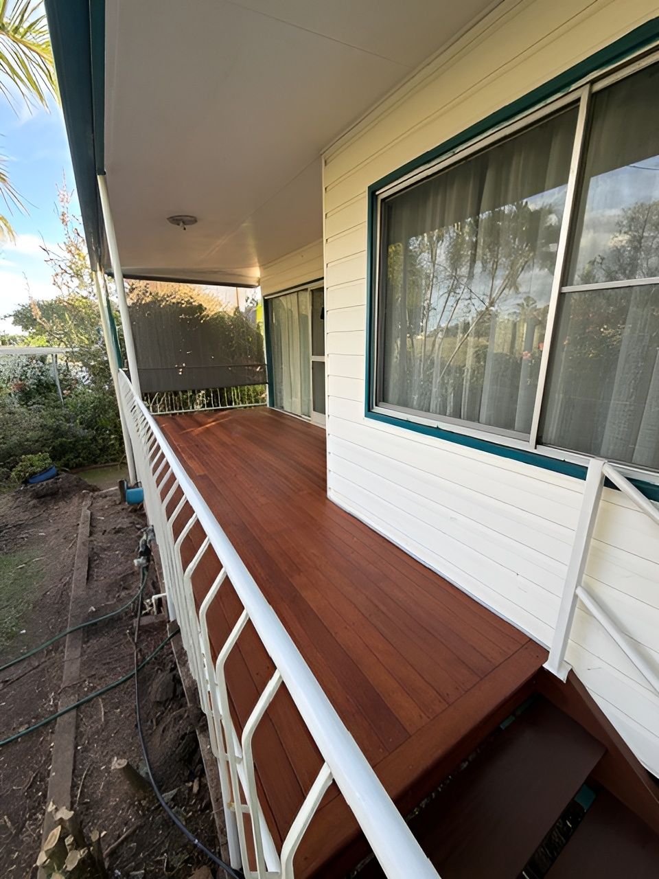 Covered Front Porch with Wooden Deck and White Railing Beside a Garden Path — Integrabuild in Bowen, QLD