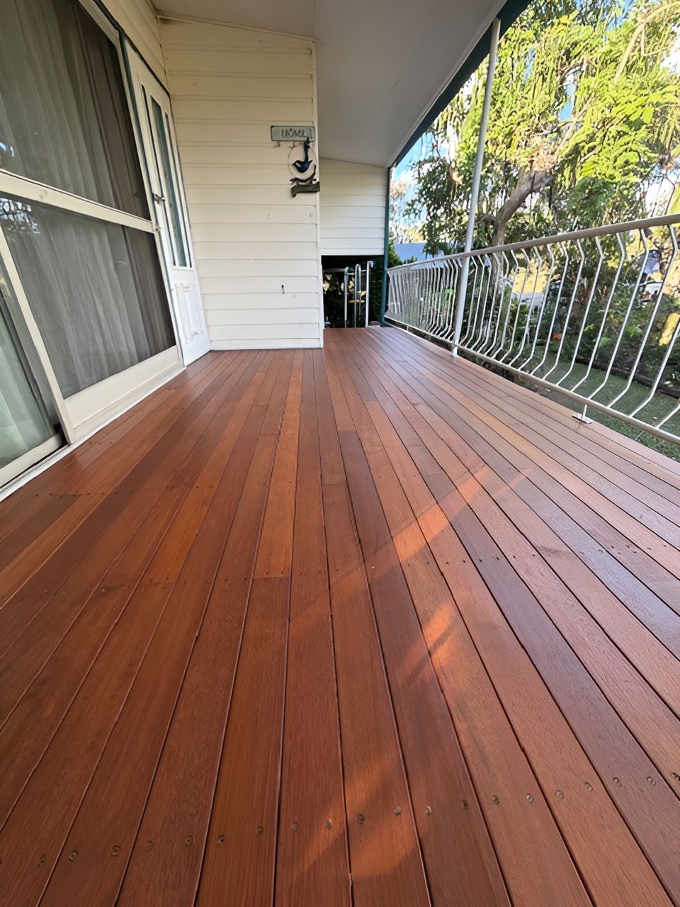 Wooden Porch Deck with White Siding and Metal Railing in Bright Daylight — Integrabuild in Bowen, QLD