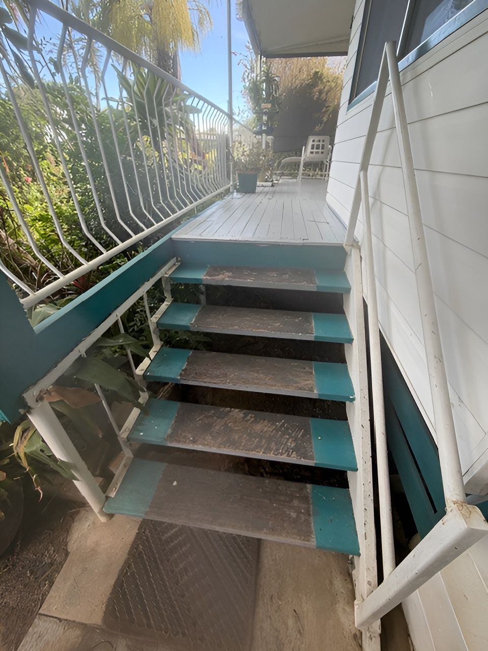 Outdoor Stairway with Teal Railings and Worn Dark Steps Beside a White House — Integrabuild in Bowen, QLD