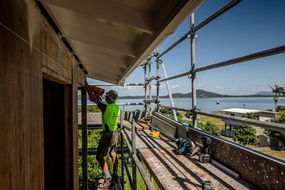 A man is standing on a scaffolding working on a building — Integrabuild in Bowen, QLD