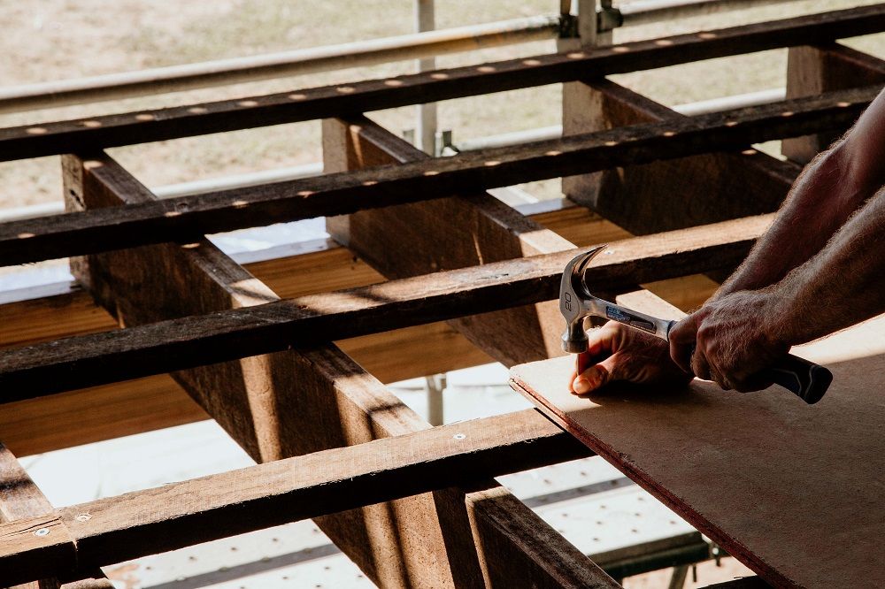A man is using a hammer to hammer a piece of wood — Integrabuild in Bowen, QLD