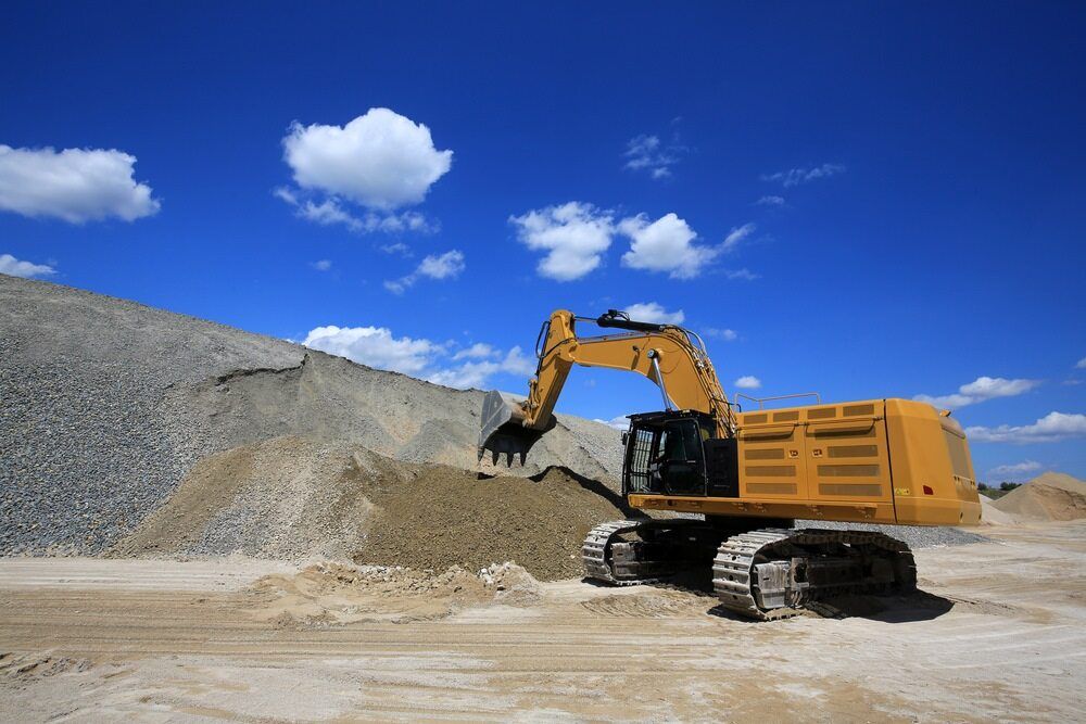Yellow Excavator Dumping Dirt at a Rocky Construction Site — Integrabuild in Bowen, QLD