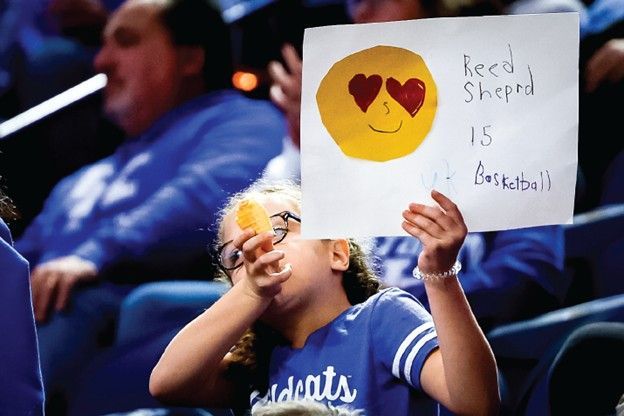 Girl at a basketball game holds sign: 