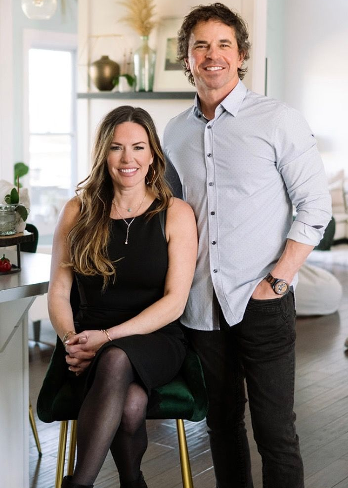A smiling man and woman pose together in a bright, modern living space.