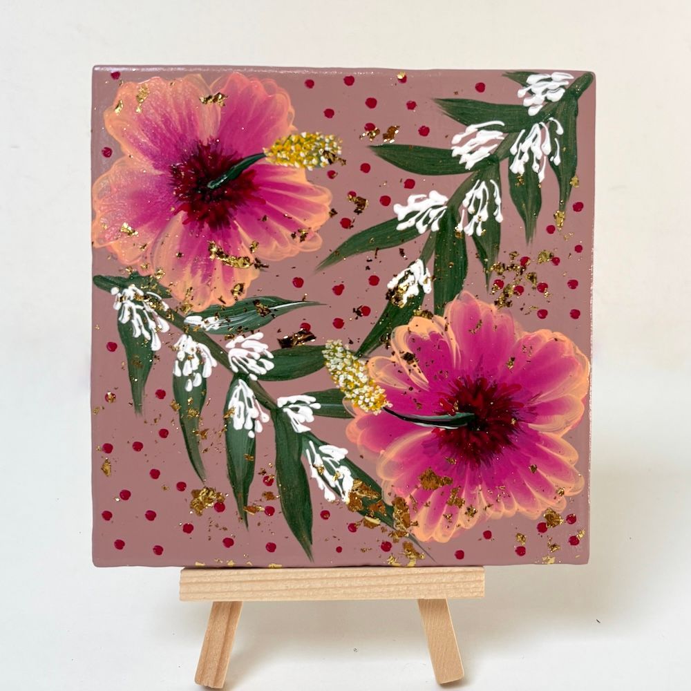 Bloemschilderij op een kleine ezel met twee roze bloemen, groene bladeren en gouden spetters op een taupekleurige achtergrond.