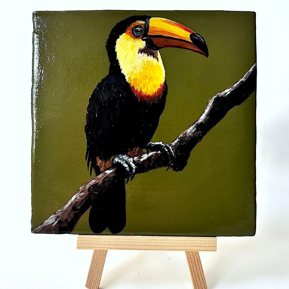 Een klein, gedetailleerd schilderij van een toekan met een felgele borst en een grote oranje snavel, zittend op een tak.