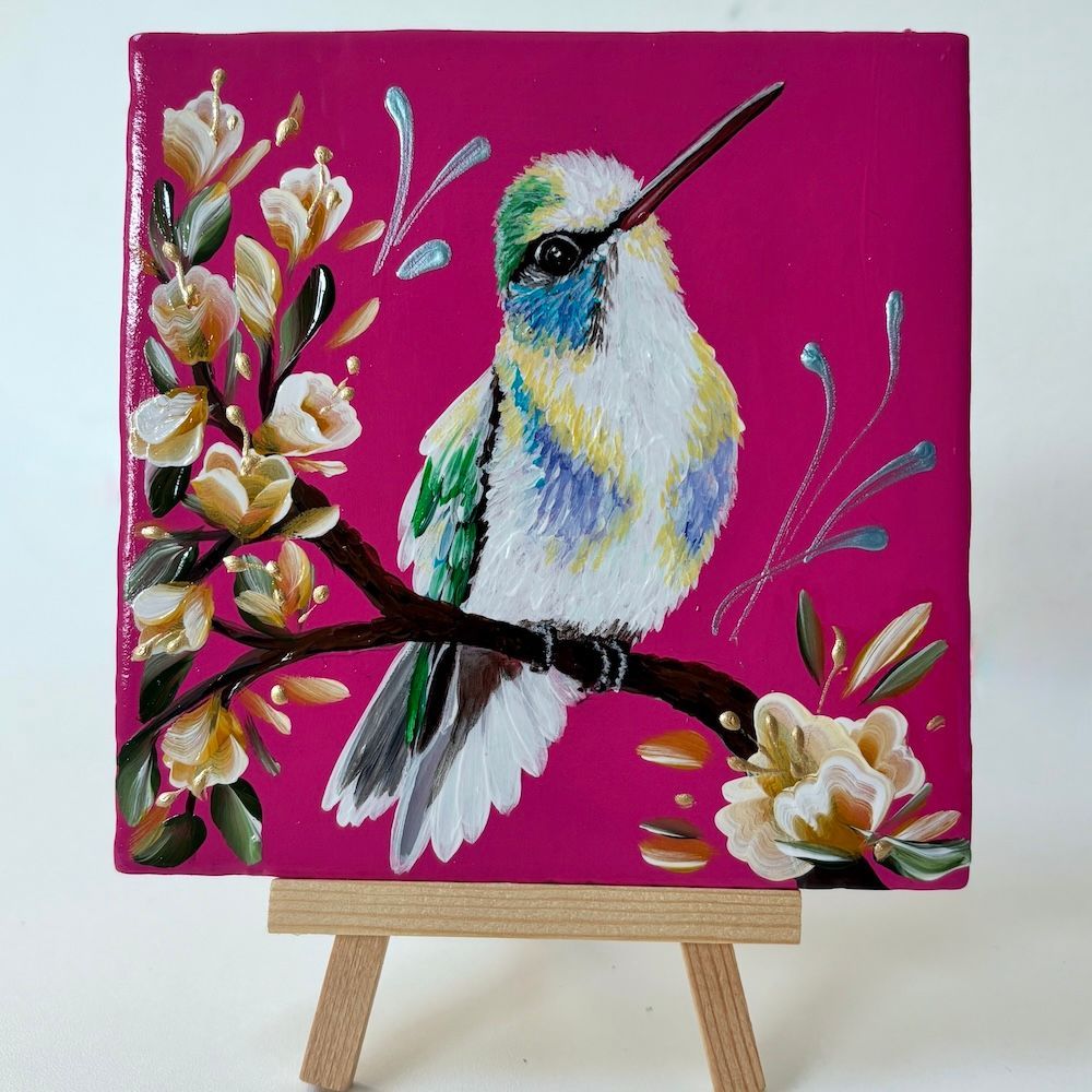 Een tegeltje met een kolibrie die op een bloeiende tak zit, tegen een levendige magenta achtergrond