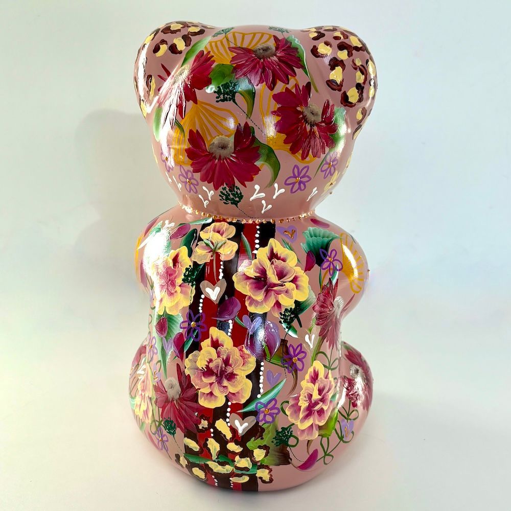 Roze keramische beerfiguur met bloemenpatroon op een effen lichte achtergrond.