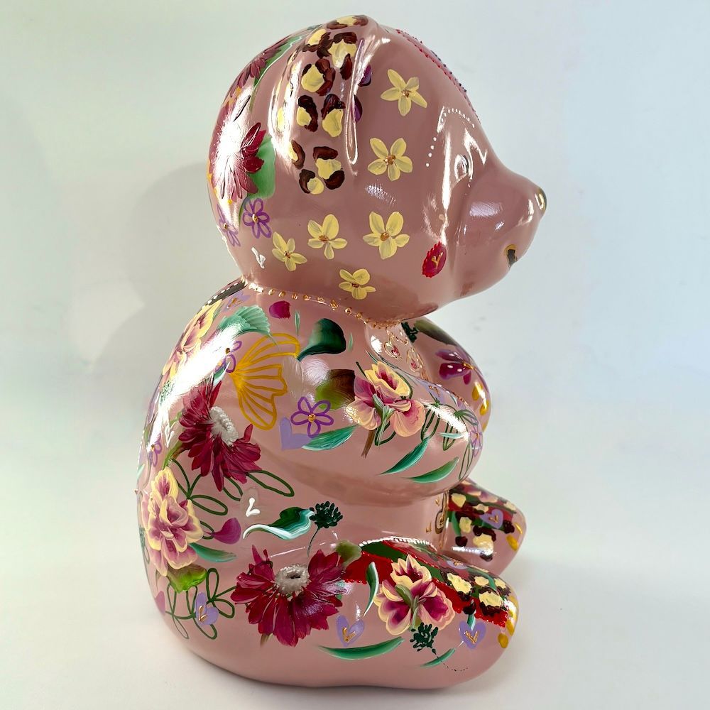 Roze keramische beerfiguur met bloemenpatroon op een effen lichte achtergrond.