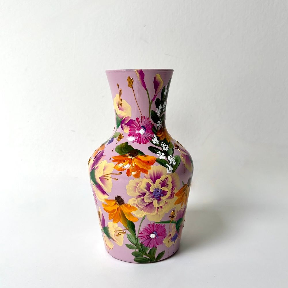 Roze vaas met bloemenmotief, beschilderd met paarse, gele en oranje bloemen op een witte achtergrond.