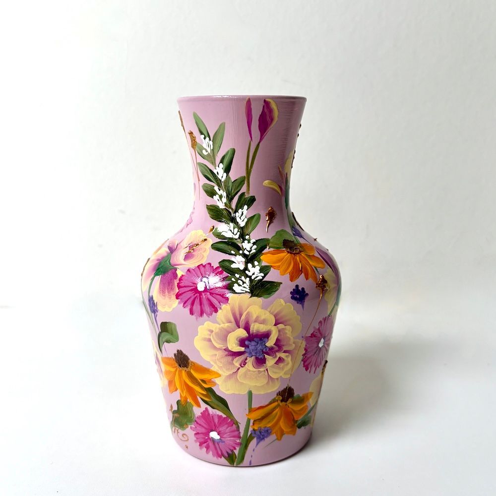 Roze vaas met bloemenmotief, beschilderd met paarse, gele en oranje bloemen op een witte achtergrond.
