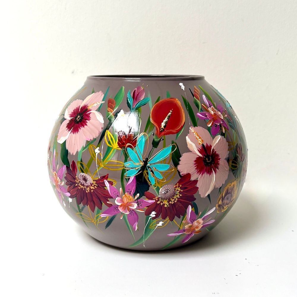 Keramische vaas met bloemenmotief, met roze, paarse en turquoise bloemen op een lichte achtergrond.