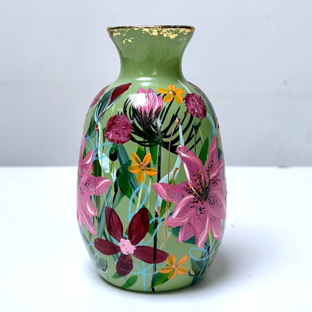 Groene vaas met kleurrijke handgeschilderde bloemen op een wit oppervlak