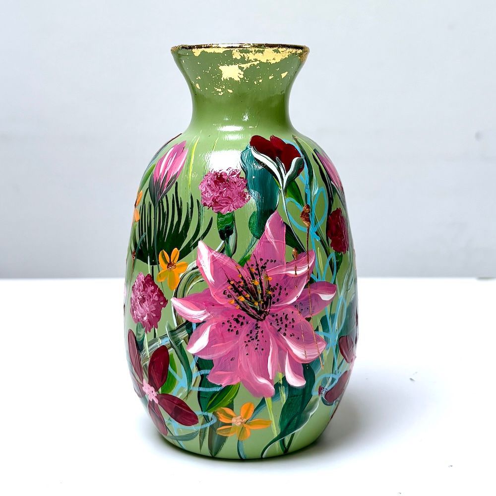 Groene vaas met kleurrijke handgeschilderde bloemen op een wit oppervlak