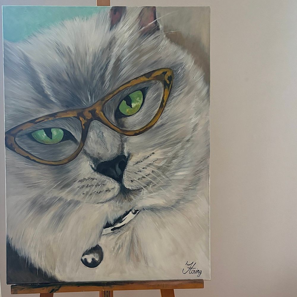 Portret van een witte kat met een bruine bril en een belletjeshalsband op een zachtgrijze achtergrond.