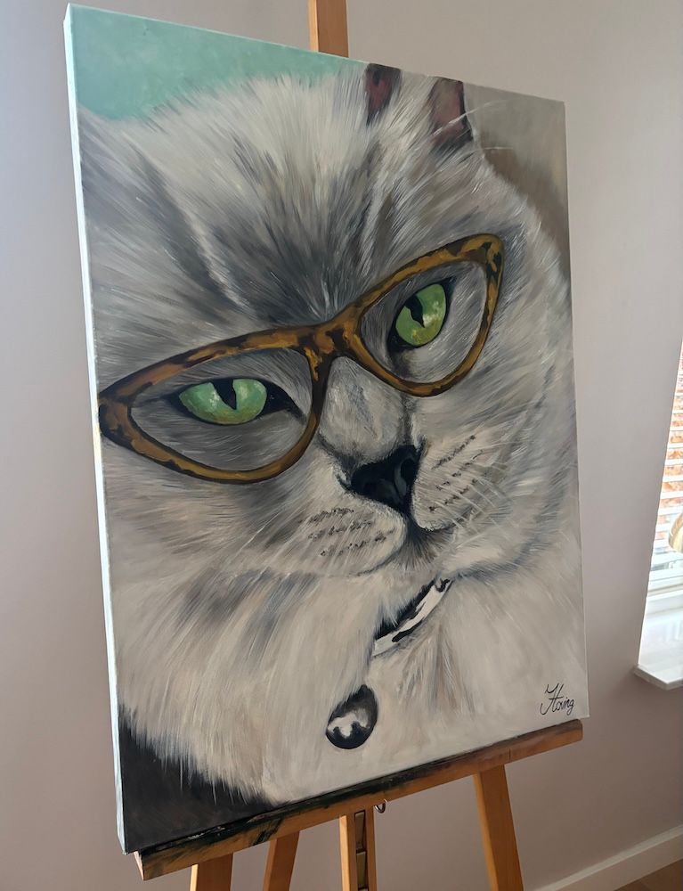 Portret van een witte kat met een bruine bril en een belletjeshalsband op een zachtgrijze achtergrond.