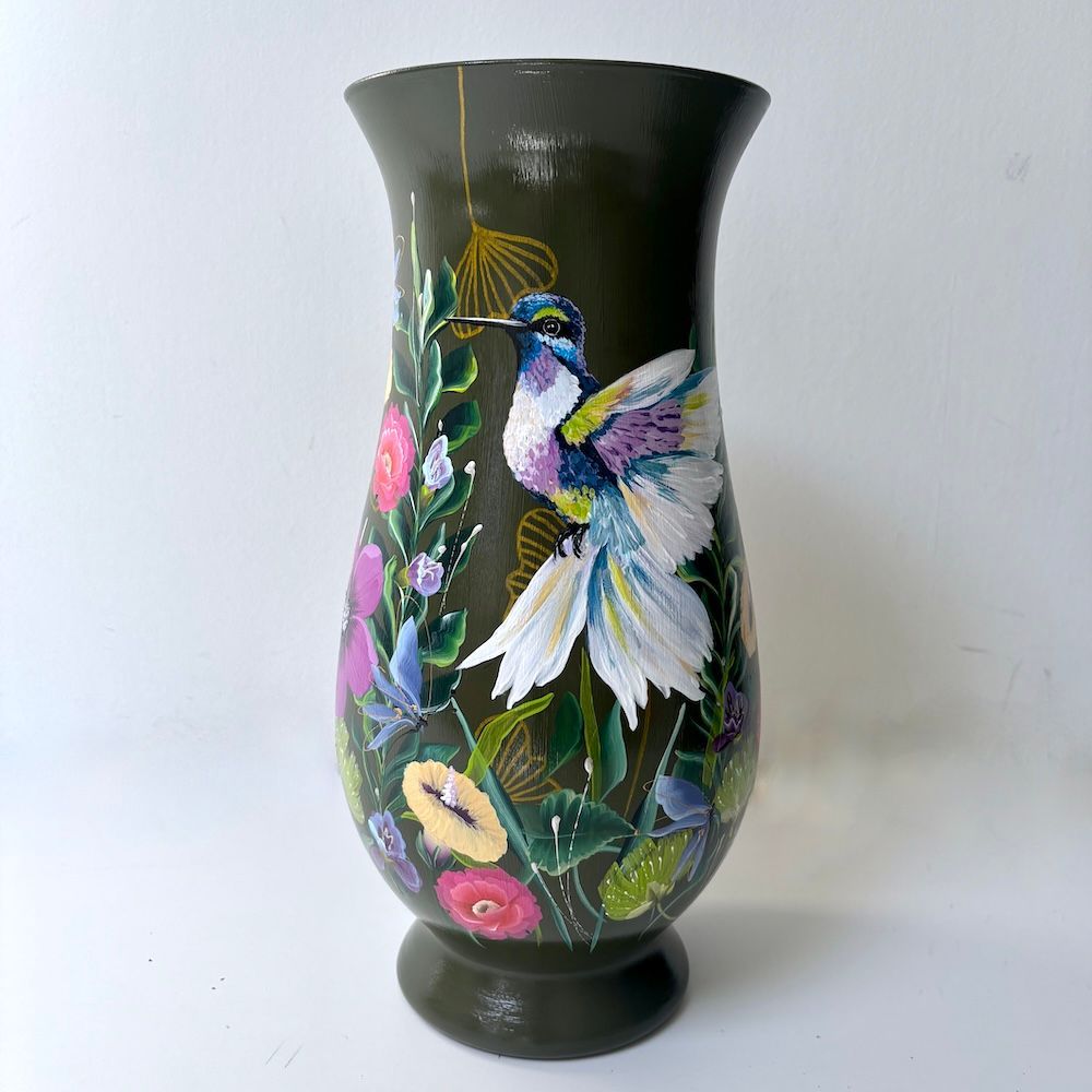 Zwarte vaas met kleurrijke, handgeschilderde kolibrie en bloemen op een witte achtergrond.