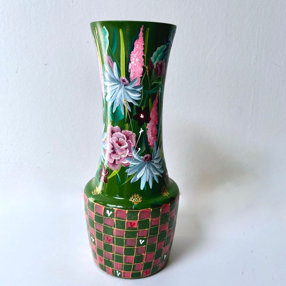 Decoratieve groene vaas met roze bloemen- en ruitpatronen op een witte achtergrond.