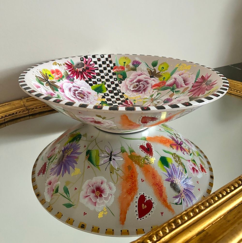 Decoratieve glazen schaal met bloemen en vlinders op een spiegelend oppervlak.