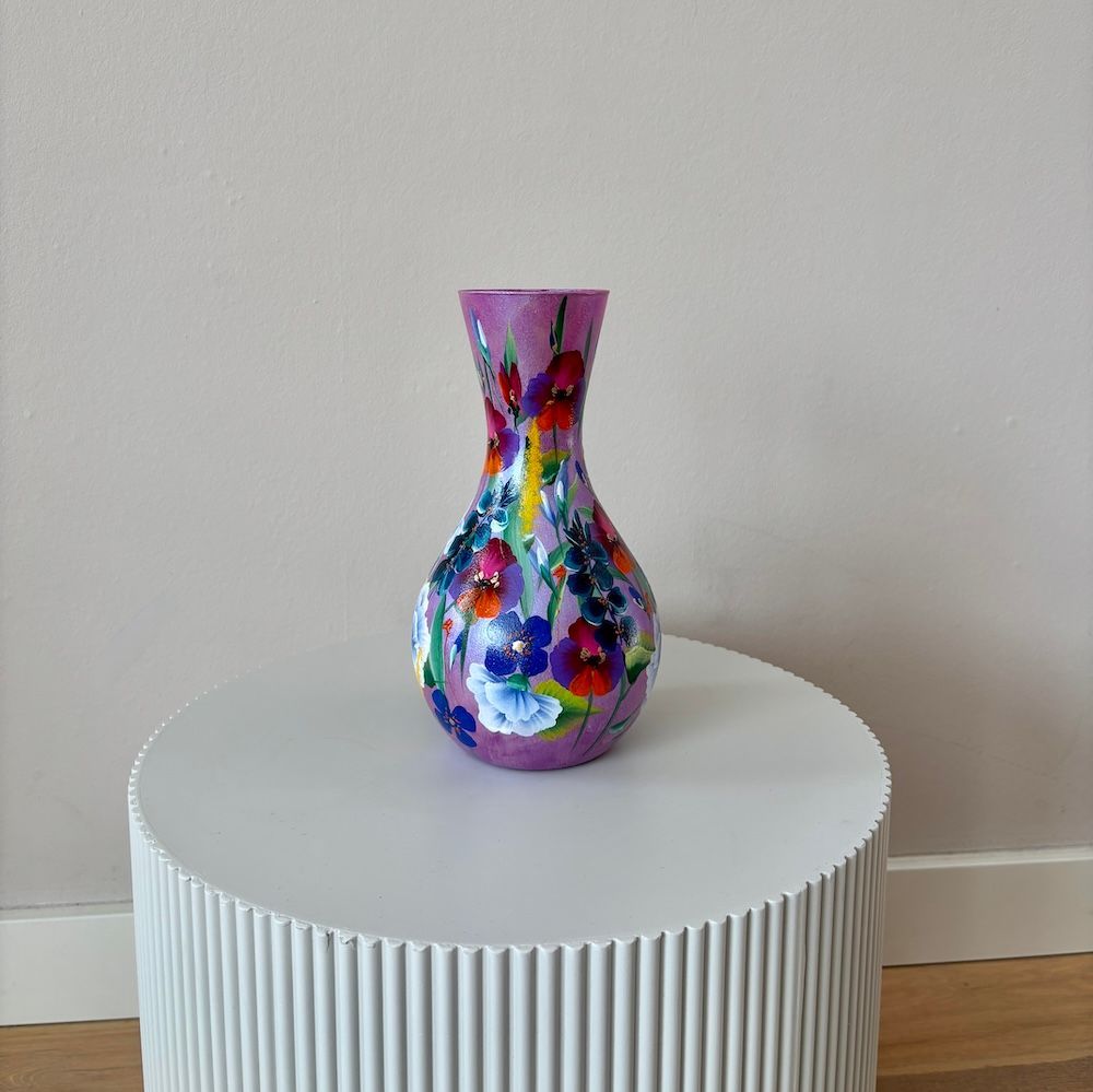 Een handbeschilderde, bolvormige, lavendelkleurige vaas met kleurrijke bloemenpatronen op een neutrale achtergrond.