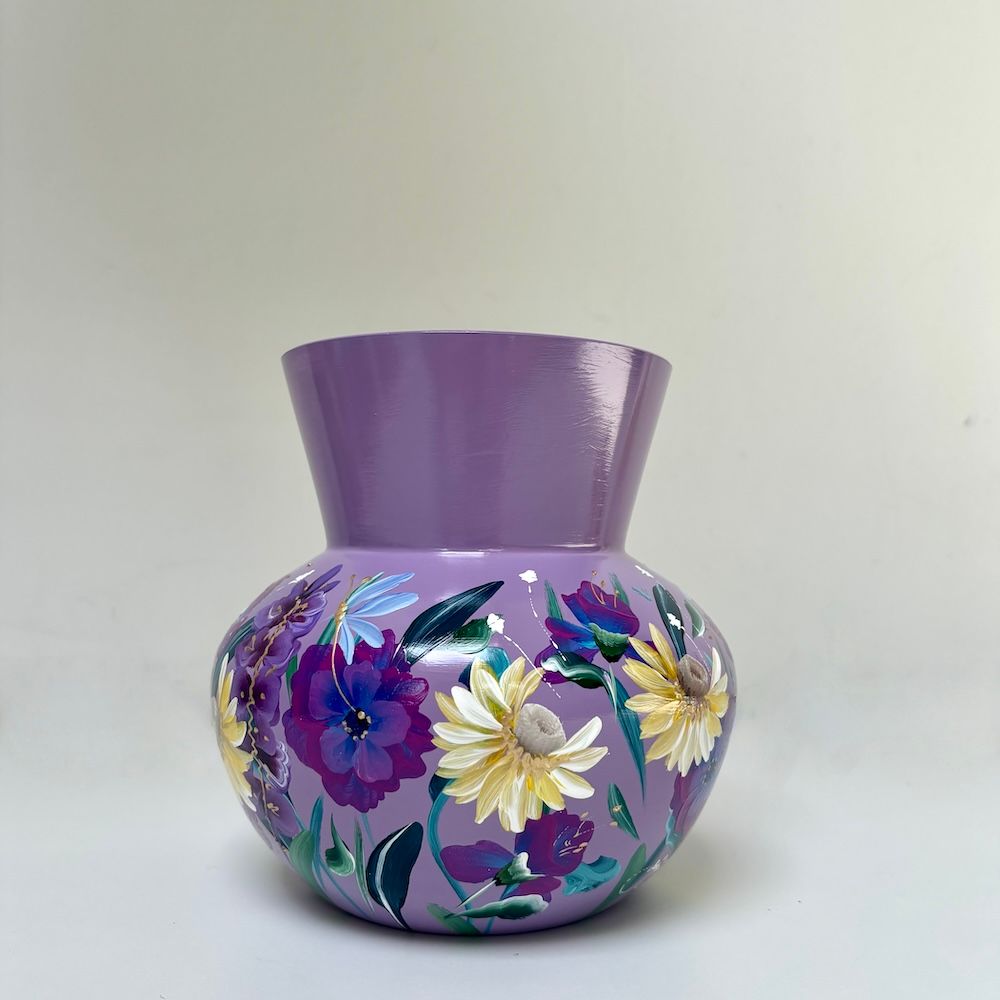 Paarse, met bloemen beschilderde keramische vaas met een uitlopende bovenkant op een lichte achtergrond.