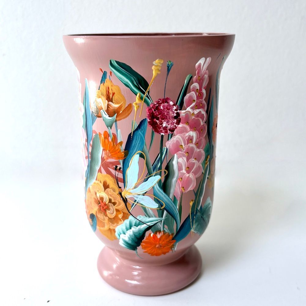 Roze keramische vaas met kleurrijke bloemen- en bladmotieven op een witte achtergrond.