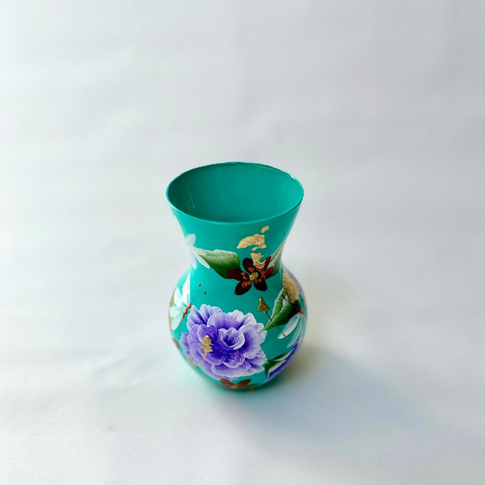 Een klein, turquoise vaasje versierd met handgeschilderde paarse bloemen, witte bloesems en een klein donker bloempje.