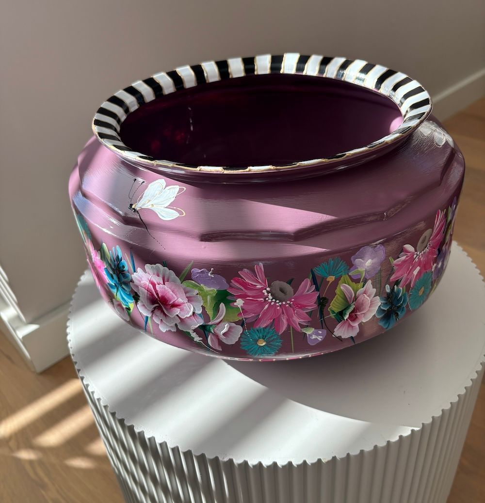 Een pruimkleurige decoratieve schaal met een zwart-wit gestreepte rand, versierd met handgeschilderde bloemmotieven