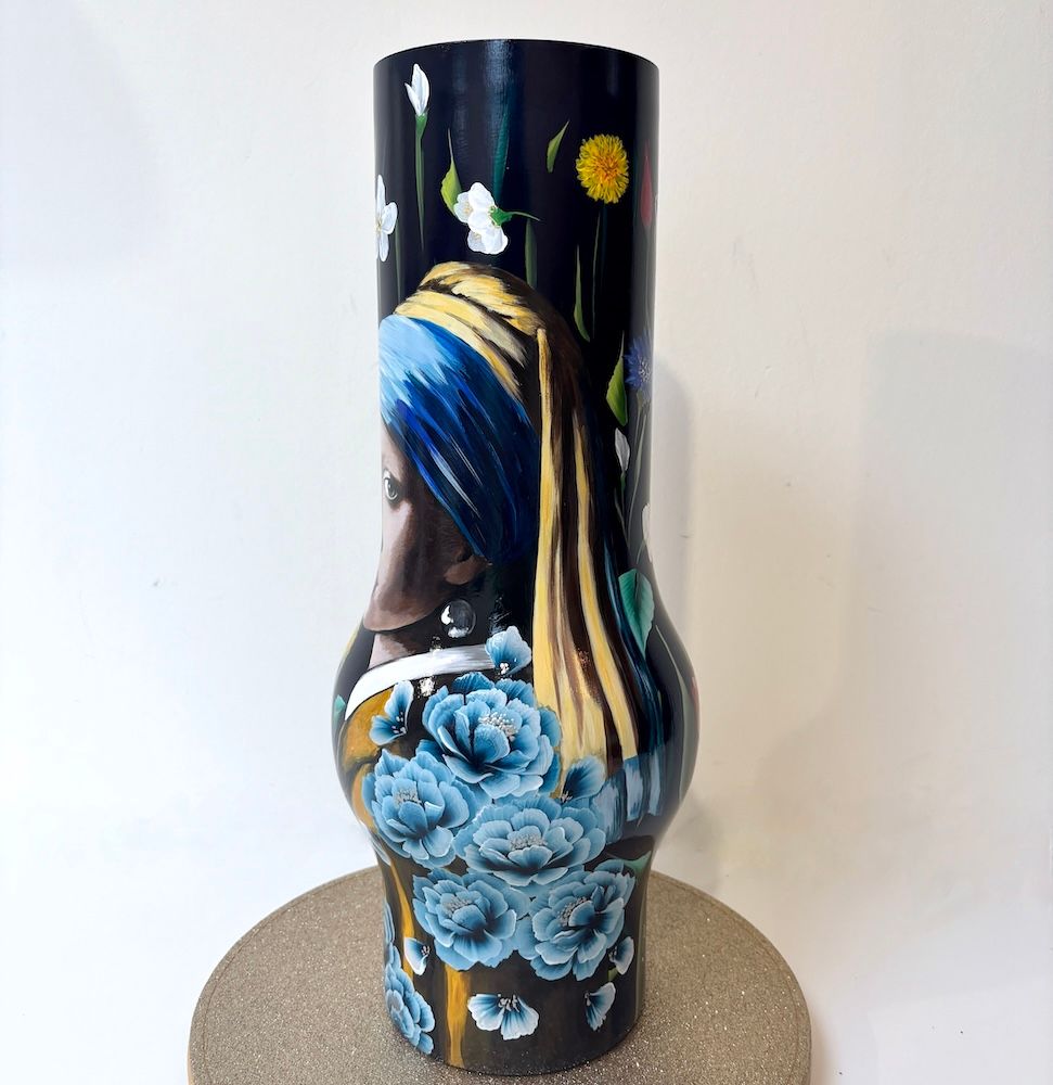 Decoratieve vaas met bloemenmotief en een portret van een vrouw met een blauwe hoofddoek.