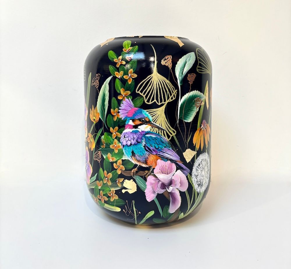 Een zwarte cilindervormige vaas versierd met een kleurrijke ijsvogel, delicate bloemen en bladgoud.