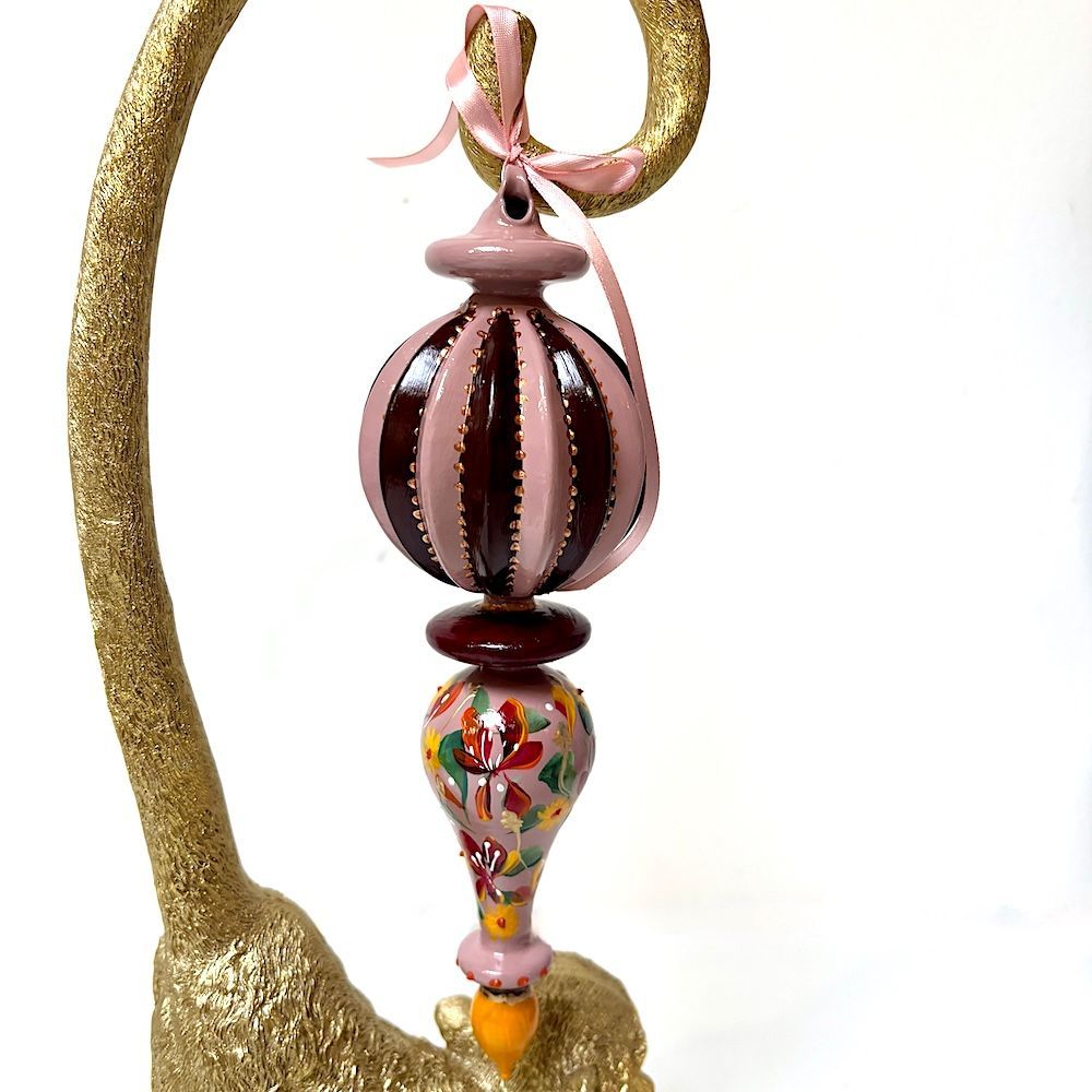 Kleurrijk hangend glazen ornament met roze, bordeauxrode, gouden en oranje kralen.