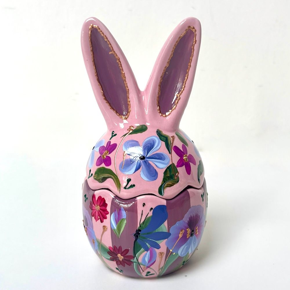 Roze keramische bloempot in de vorm van een konijn met bloemenmotief en bijpassende kopje met geschulpte rand op een witte achtergrond.
