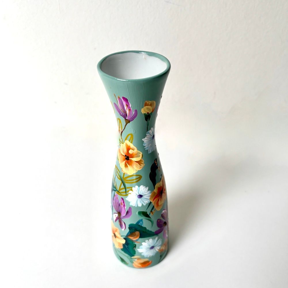Hoge turquoise vaas met kleurrijk bloemenpatroon op een witte achtergrond