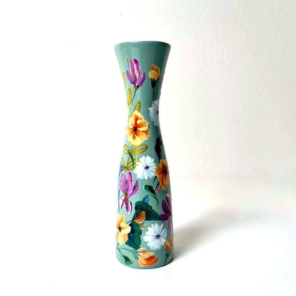 Hoge turquoise vaas met kleurrijk bloemenpatroon op een witte achtergrond
