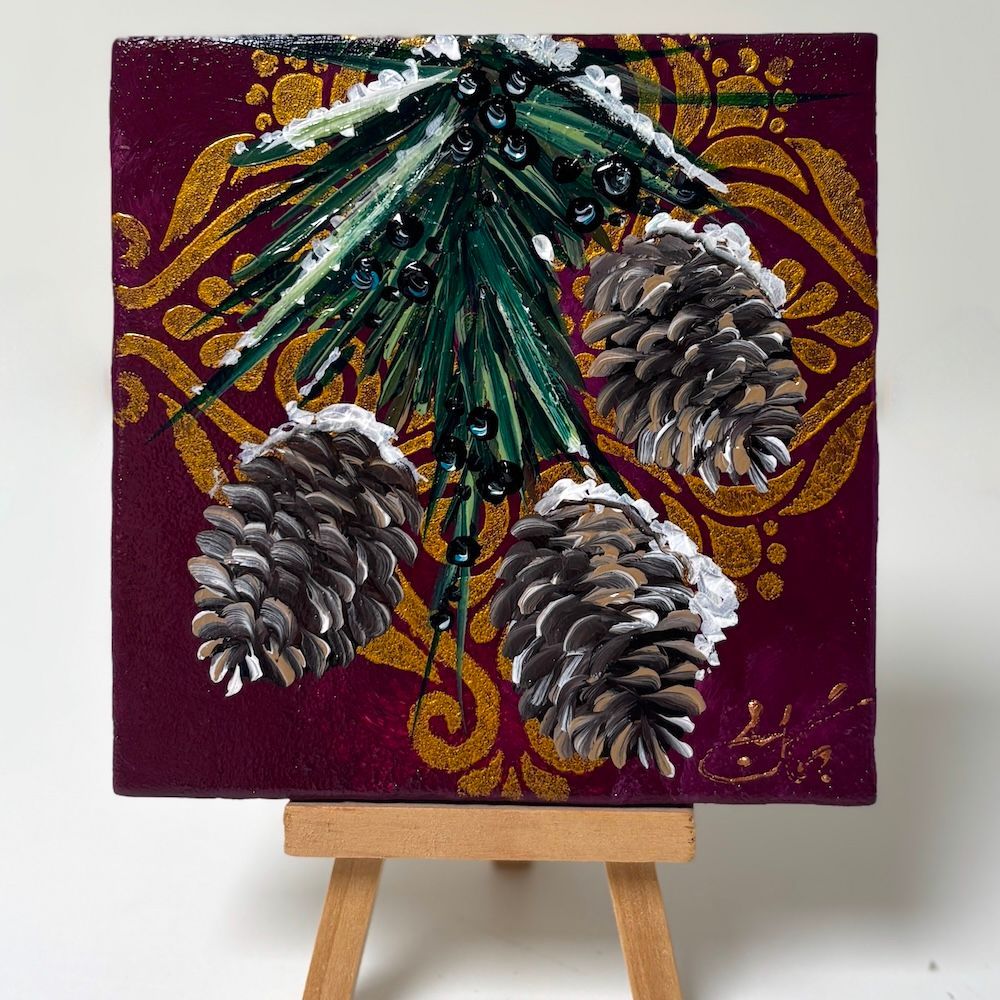 Schilderij van winterse dennenappels op bordeauxrood canvas, met groene dennentakjes en gouden decoratieve krullen op een schildersezel.