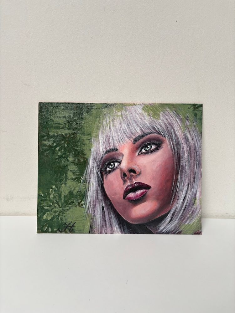 Gestileerd portret van een vrouw met zilverkleurig haar en donkere make-up tegen een groene, gestructureerde achtergrond.