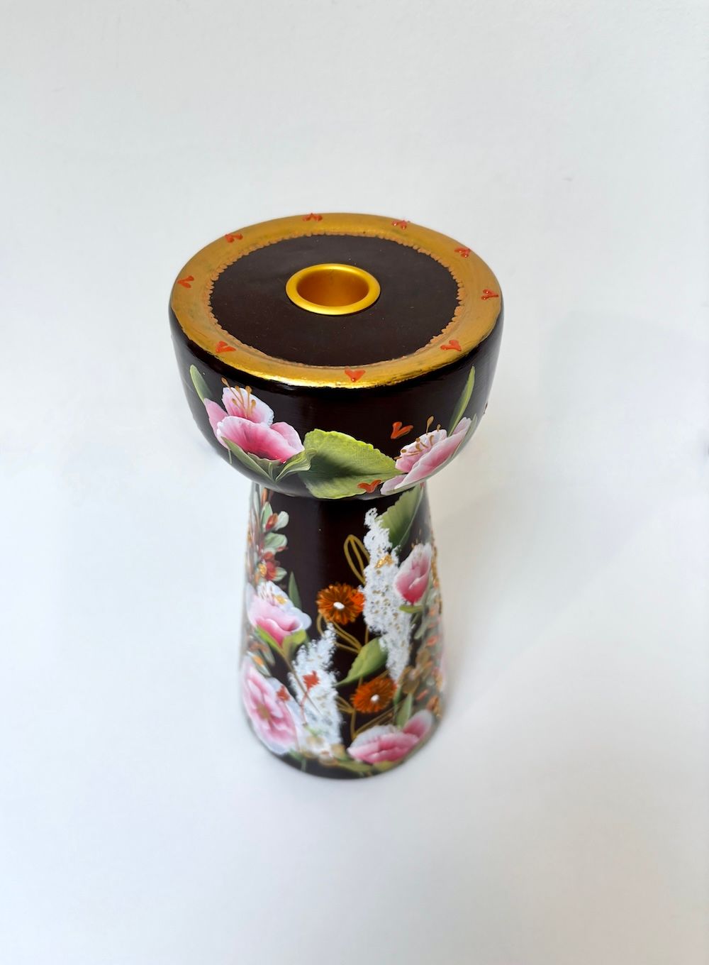 Een donkerbruine keramische kandelaar handbeschilderd met kleurrijke bloemmotieven.