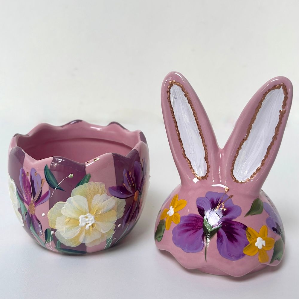 Roze keramische eierdop met bloemenmotief en bloempotje in de vorm van een konijntje op een witte achtergrond.
