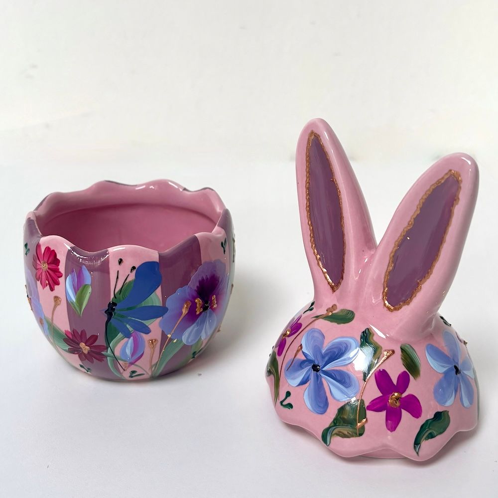 Roze keramische bloempot in de vorm van een konijn met bloemenmotief en bijpassende kopje met geschulpte rand op een witte achtergrond.