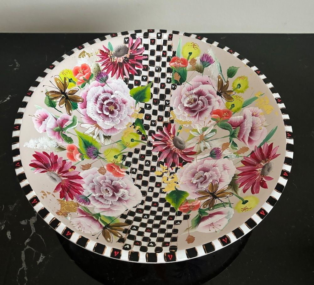 Decoratieve glazen schaal met bloemen en vlinders op een spiegelend oppervlak.