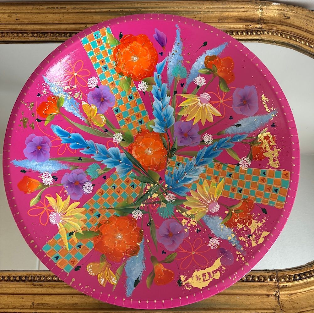 Twee kleurrijke, gedecoreerde kommen op elkaar gestapeld, roze op turquoise met bloemen- en abstracte patronen.
